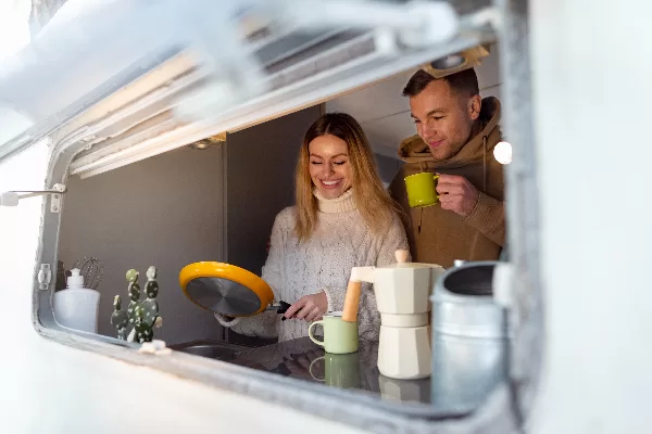 Un couple fait la cuisine dans un van aménagé